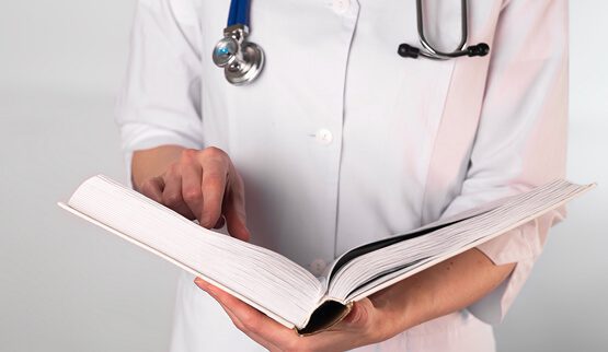 A doctor's hands reviewing notes on a clipboard with a stethoscope and medical chart, symbolizing professional healthcare marketing and strategy.