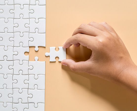 Two hands fitting the last piece into a white jigsaw puzzle, symbolizing the successful completion of a complex digital transformation project, solving a challenge, or a partnership bringing all elements together.