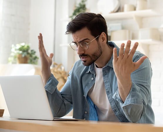 A distressed man sitting at a desk with his hands holding his head in frustration, symbolizing the complexities and challenges of managing a multi-lingual, high-stakes professional association portal.