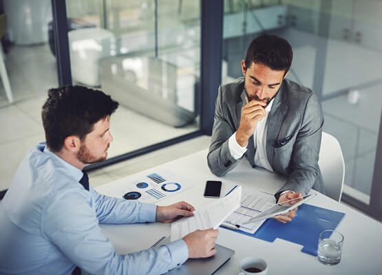 Two business professionals having a focused discussion over a laptop in a modern office, symbolizing consulting, strategy, and collaborative project planning.