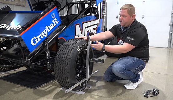 QuickTrick Alignment Case Study image showing a mechanic working on a race car wheel with their equipment, highlighting Automotive Tools & Accessories and custom product modules.