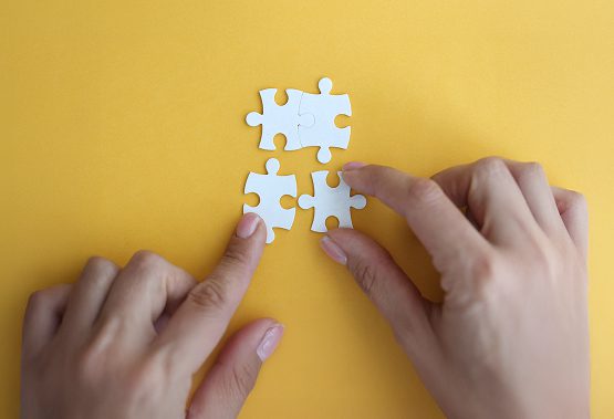 Hands arranging puzzle pieces representing technology approach and framework selection for MVP development
